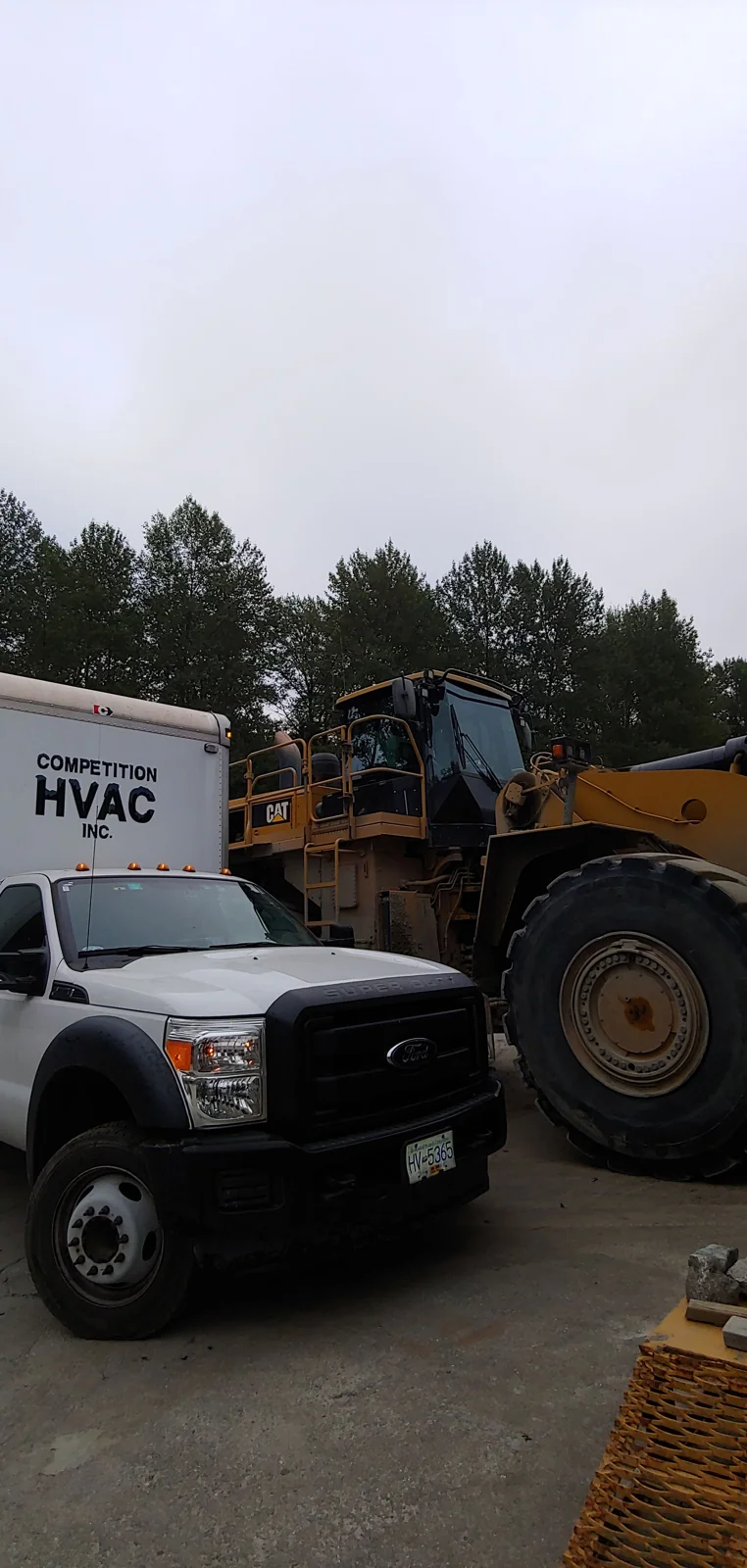 Competition HVAC service truck beside heavy equipment at a job site